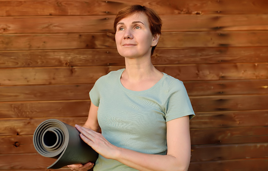 Middle aged woman holding a yoga mat