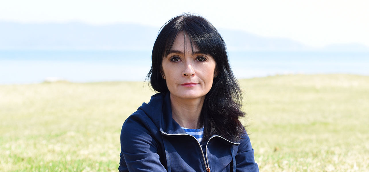 Dark haired middle aged woman posing in front of crop field