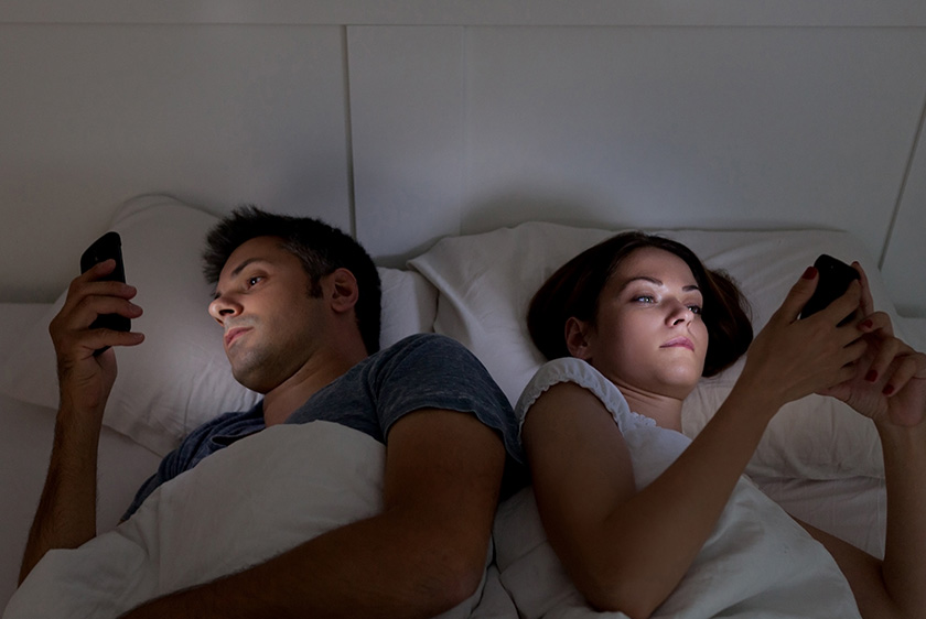 Couple in bed looking at their phones