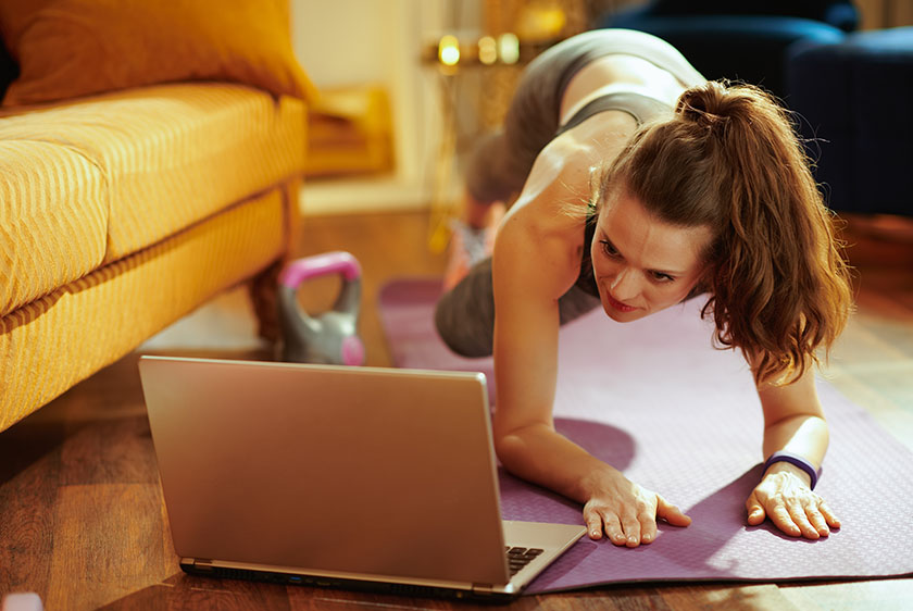 Woman exercising while looking at laptop