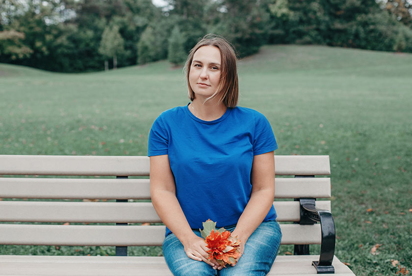 Woman in blue shirt sitting on a bench