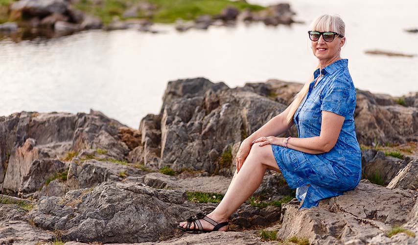 Middle aged woman in shades sitting on a rock