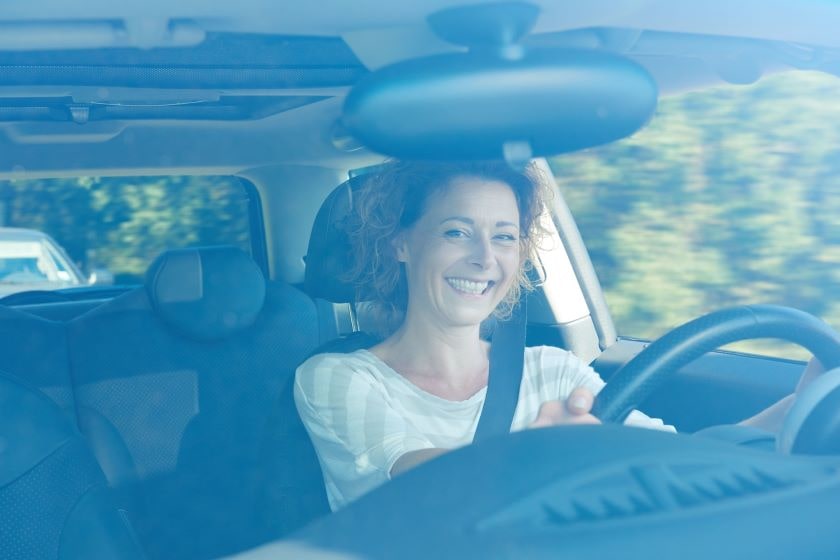 Smiling middle aged woman driving a car