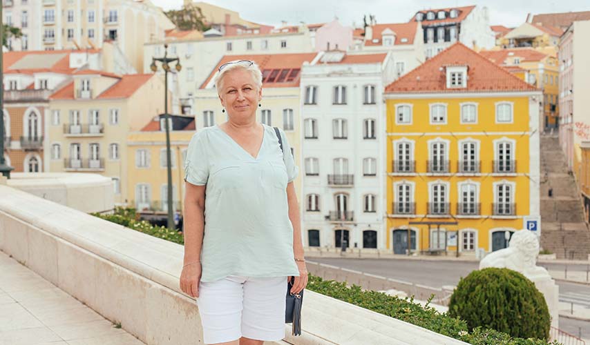 Smiling white haired elder woman posing by old architecture