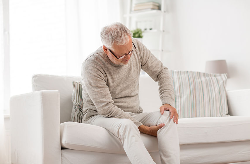 older man holding knee with pain