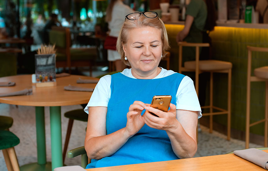 Middle aged woman in blue vest scrolling her phone