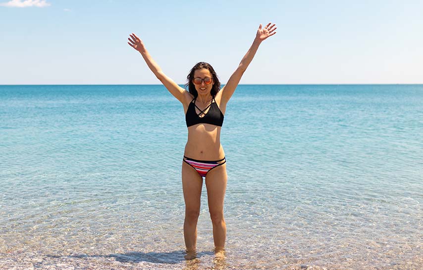 Woman raising hands and posing at the beach