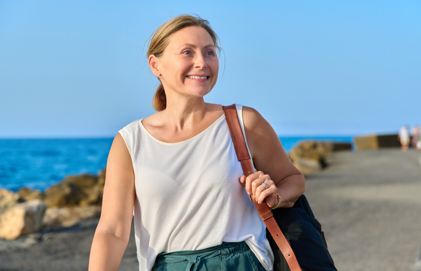 Smiling middle aged blond woman by the sea
