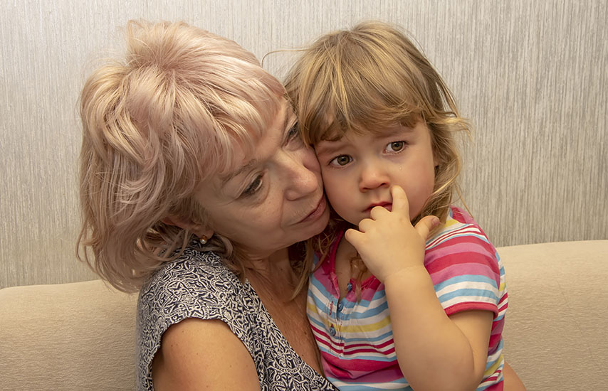 Older blond haired woman holding a child