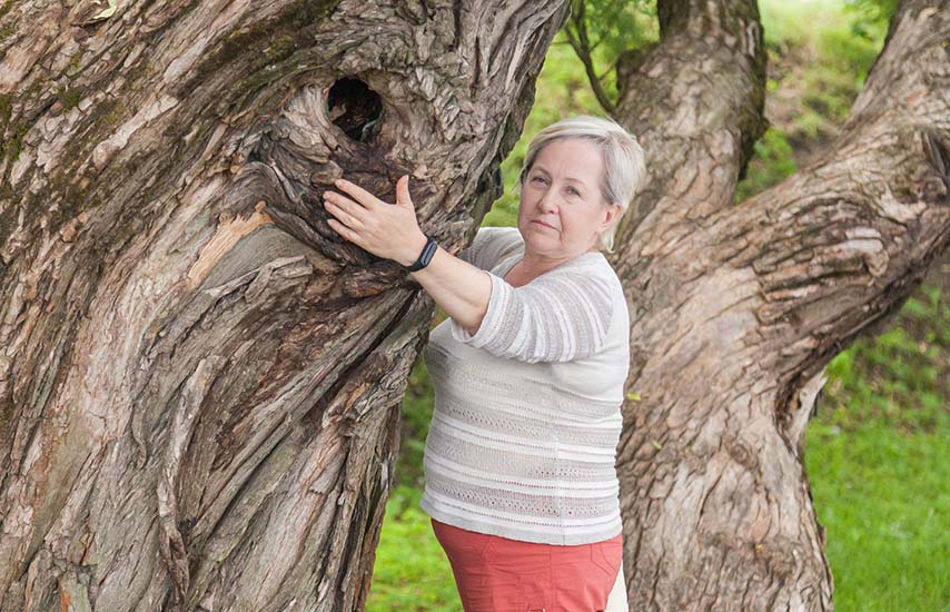 Older age woman posing by the tree