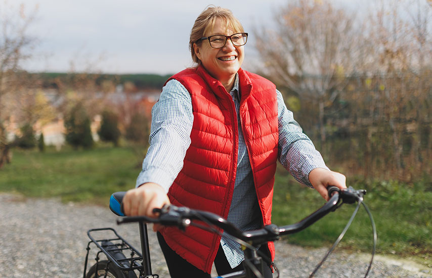 Woman in red vest holding the bicycle